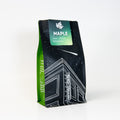Coffee bag with green and black design on a white background labeled Maple flavor