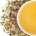 A cup of tea with chamomile, rosehips, and other herbal ingredients visible in the foreground.